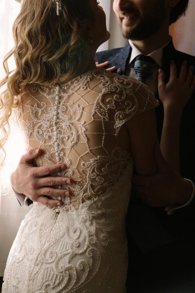 Close-up of a bride and groom embracing, highlighting the delicate details of the wedding dress — intimate moment at a seaside wedding in Barcelona